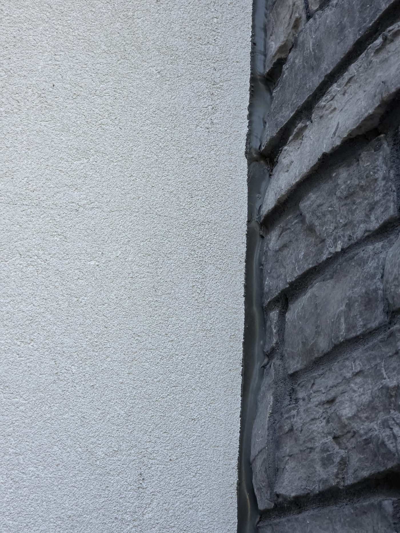 Sealant joint between stucco and stone veneer on a Jamestown home